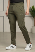 Person wearing olive green jogger pants with a brand logo and white sneakers indoors.