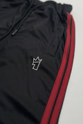 Black tracksuit with red side stripe on a light gray background