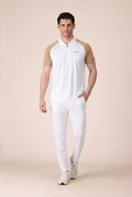 Man wearing a white polo shirt with brown sleeves and white pants on a beige background