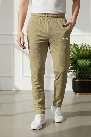 Person wearing beige corduroy pants with a brand logo, standing indoors.