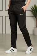 Person wearing black jogger pants with a brand logo and white sneakers in a minimal indoor setting.