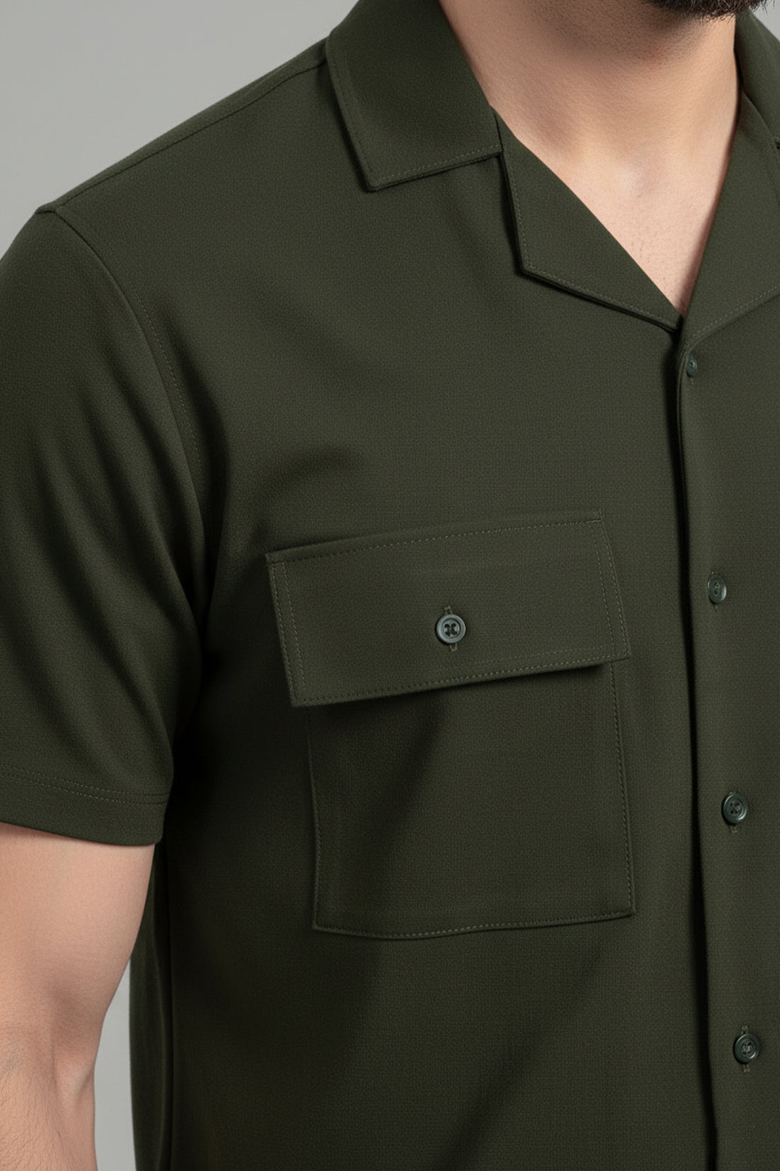 Close-up of a green shirt with a pocket and buttons on a neutral background