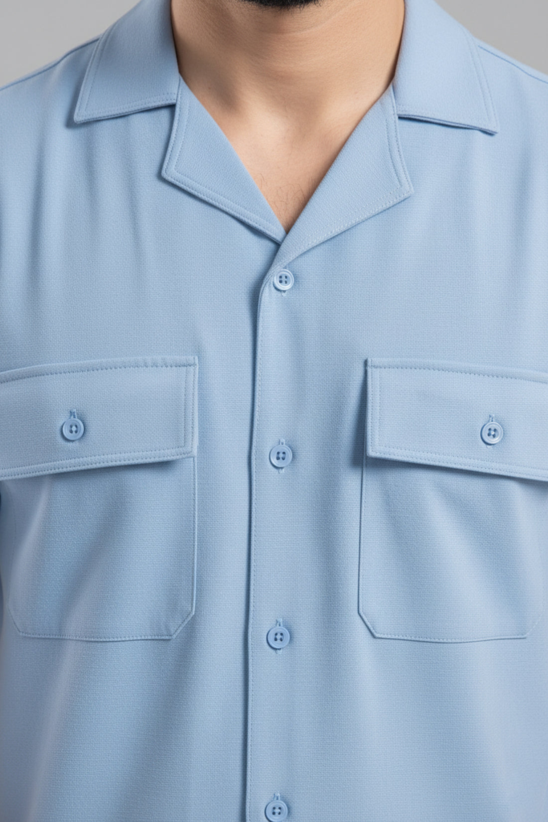 Light blue shirt with two front pockets and buttons on a neutral background