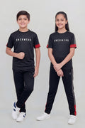 Two children wearing matching black outfits with red accents, standing side by side on a plain background.