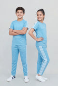 Two children wearing matching blue tracksuits with white stripes on a light gray background