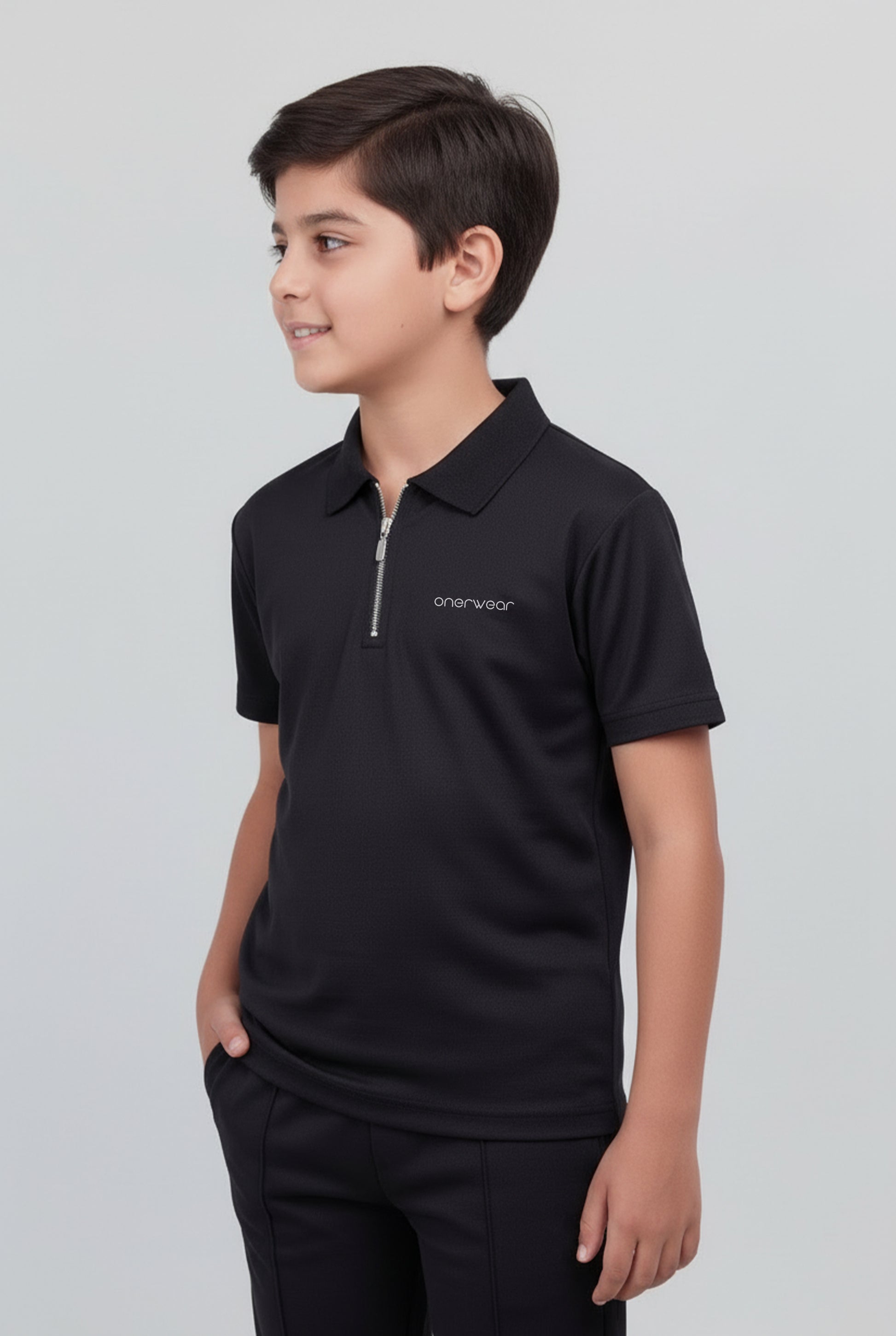 Child wearing a black polo shirt with a logo on a light gray background