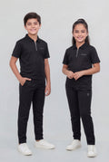 Two children wearing matching black outfits on a plain background