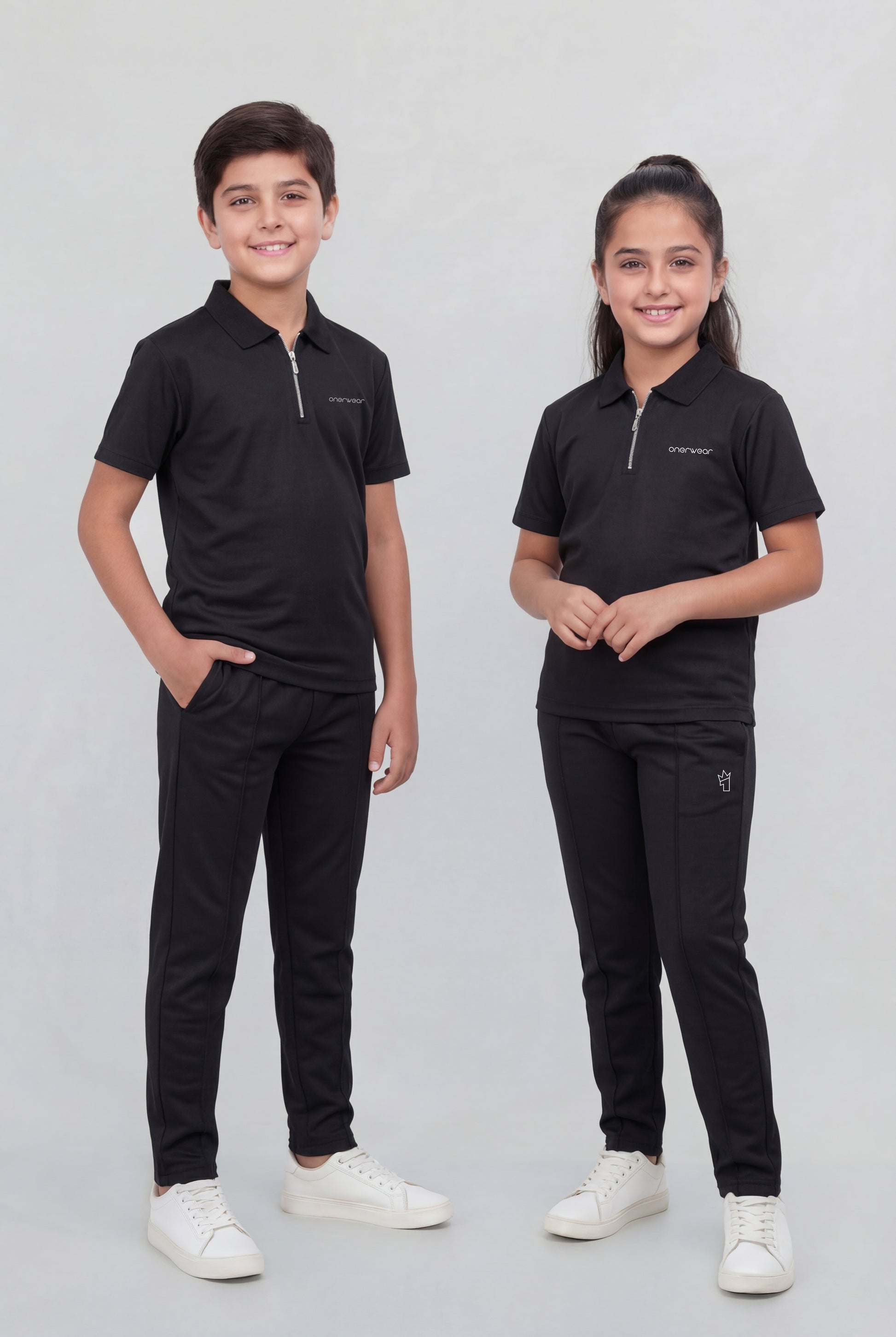 Two children wearing matching black outfits on a plain background