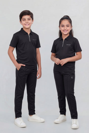 Two children wearing matching black outfits on a plain background