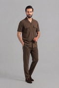 Man wearing a brown shirt and pants on a gray background