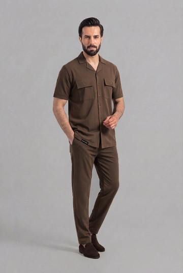 Man wearing a brown shirt and pants on a gray background