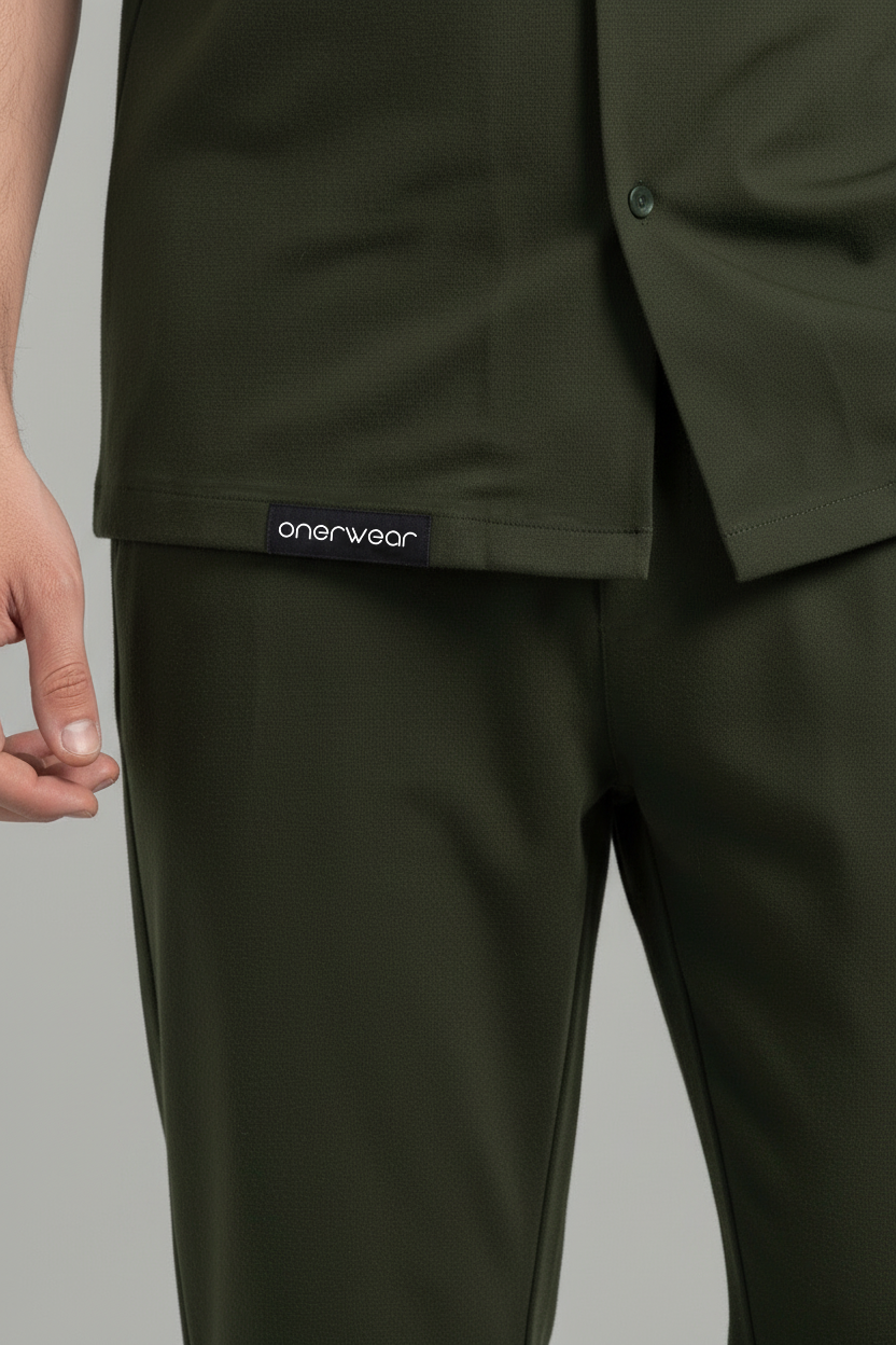 Green scrub top and pants with 'oinerwear' label on a gray background