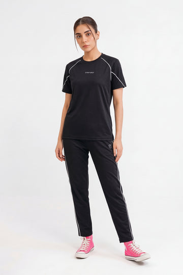 Woman wearing a black athletic outfit with pink shoes on a white background