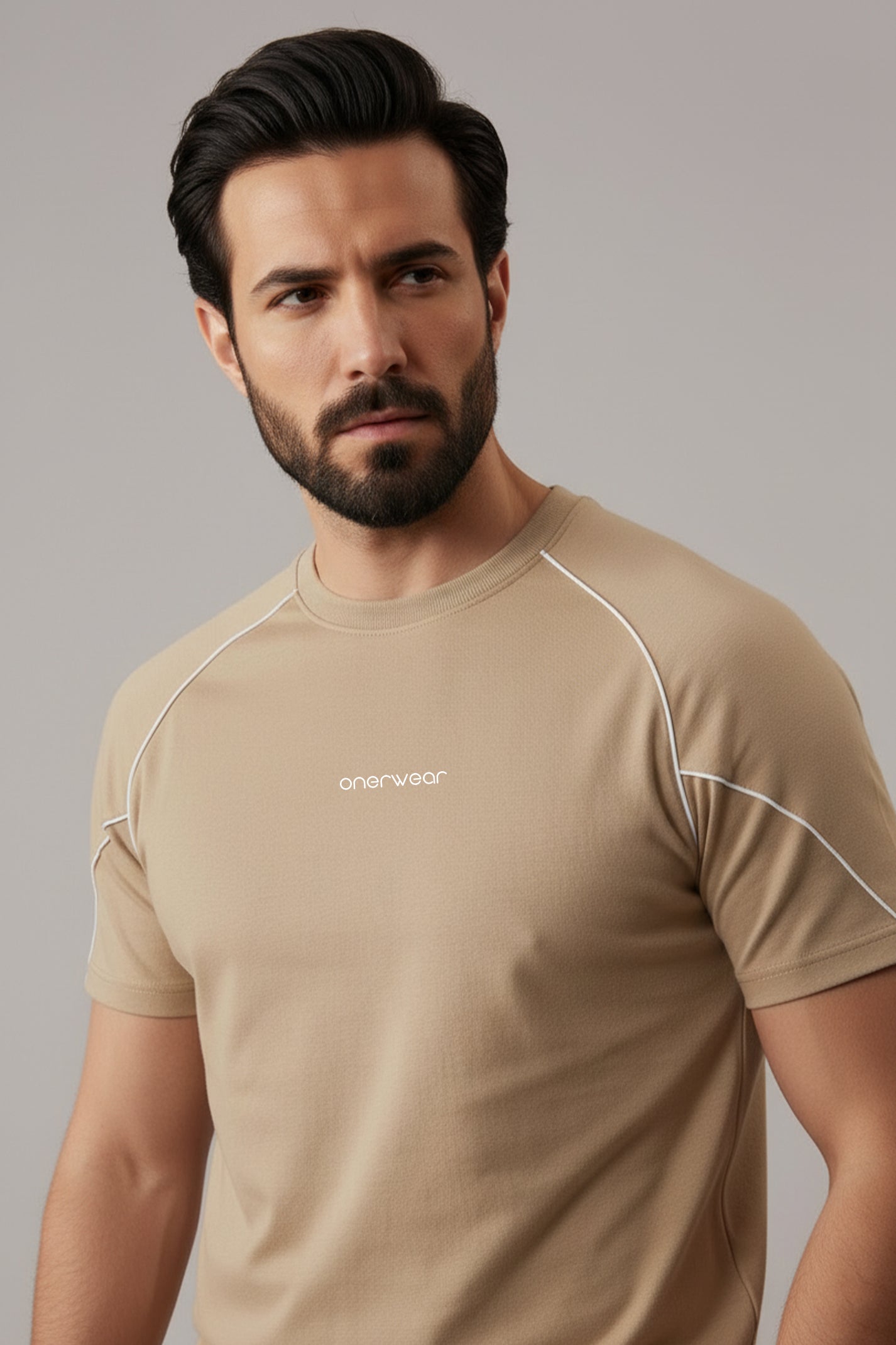 Man wearing a beige athletic shirt with a brand logo on a gray background