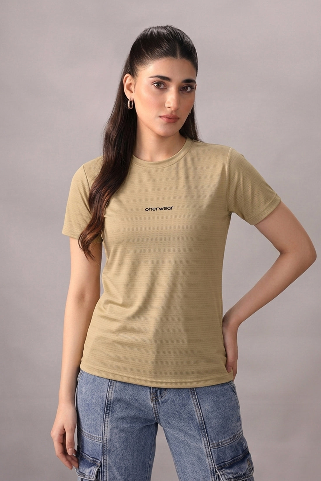 Woman wearing a beige t-shirt with a logo on a gray background