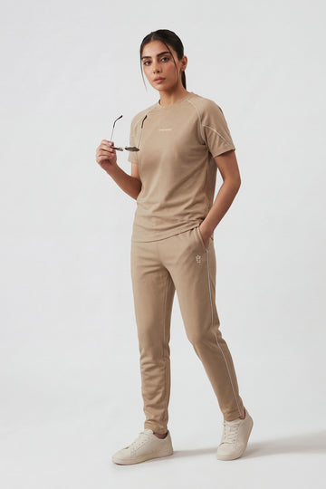 Woman wearing a beige outfit with sunglasses on a white background