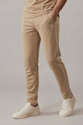 Beige pants with a white stripe worn by a person on a plain background