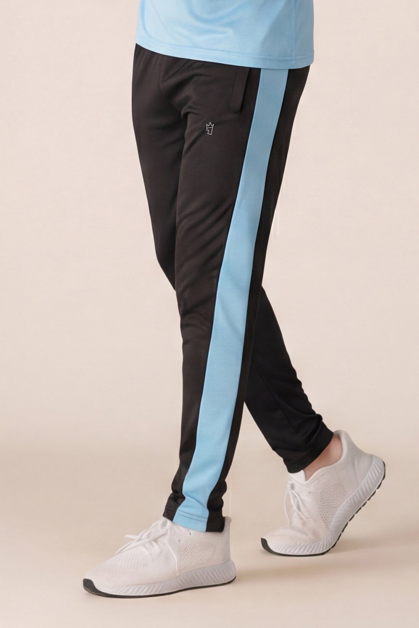 Person wearing black pants with blue stripes and a light blue shirt on a beige background