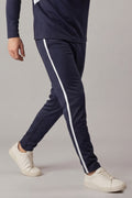 Navy tracksuit with white stripes worn by a person on a gray background