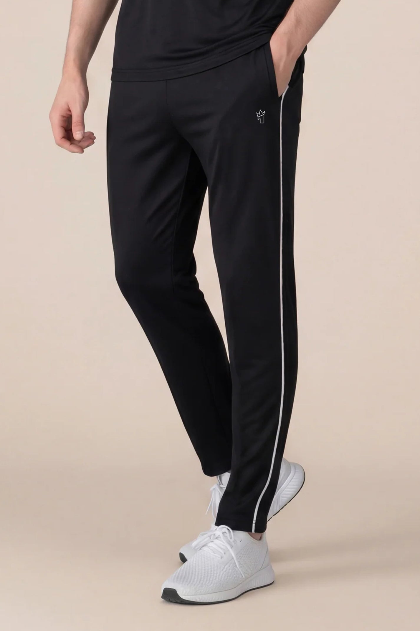 Person wearing black track pants with white stripes on a beige background