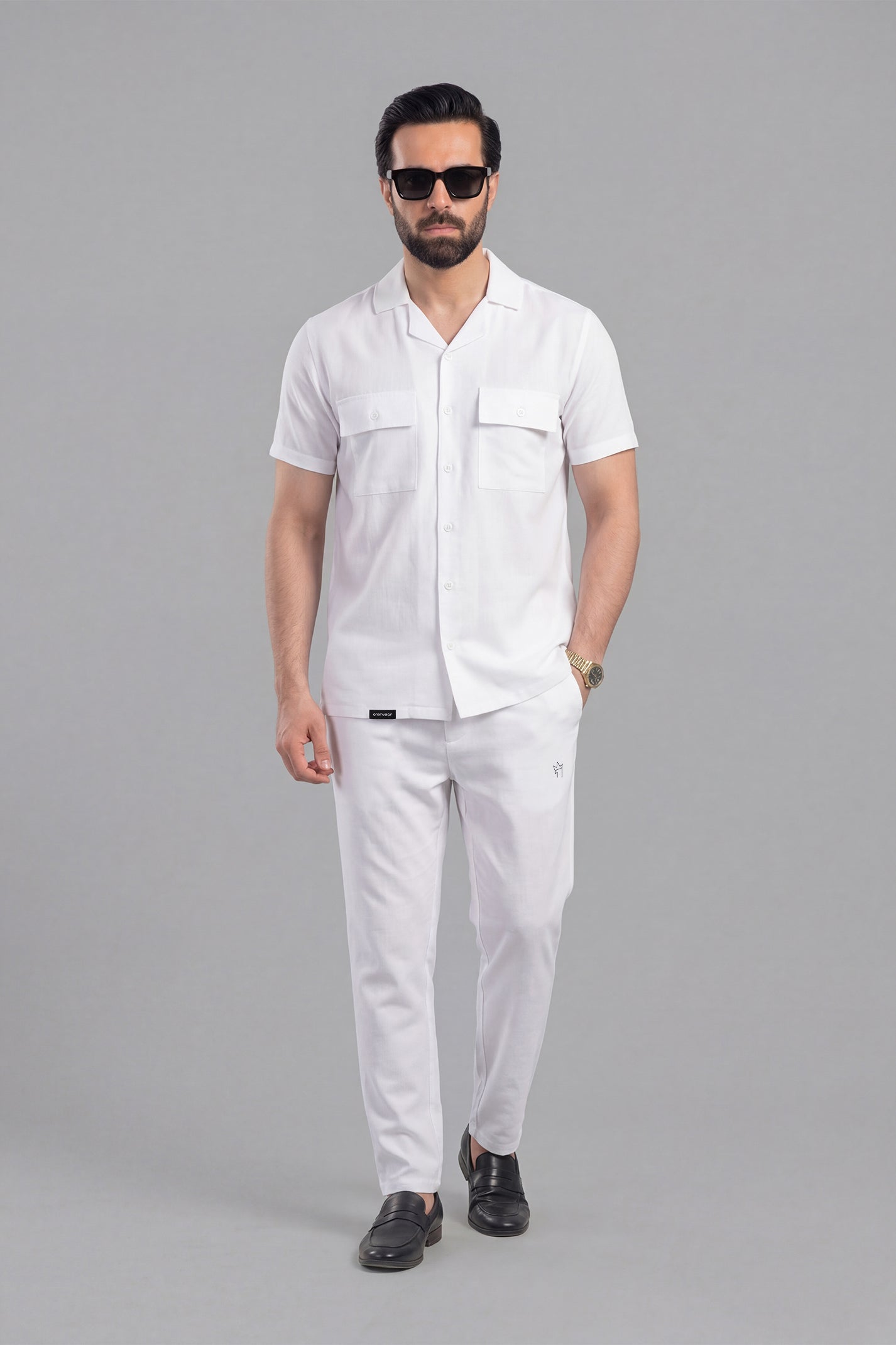 Man wearing a white outfit with sunglasses on a gray background