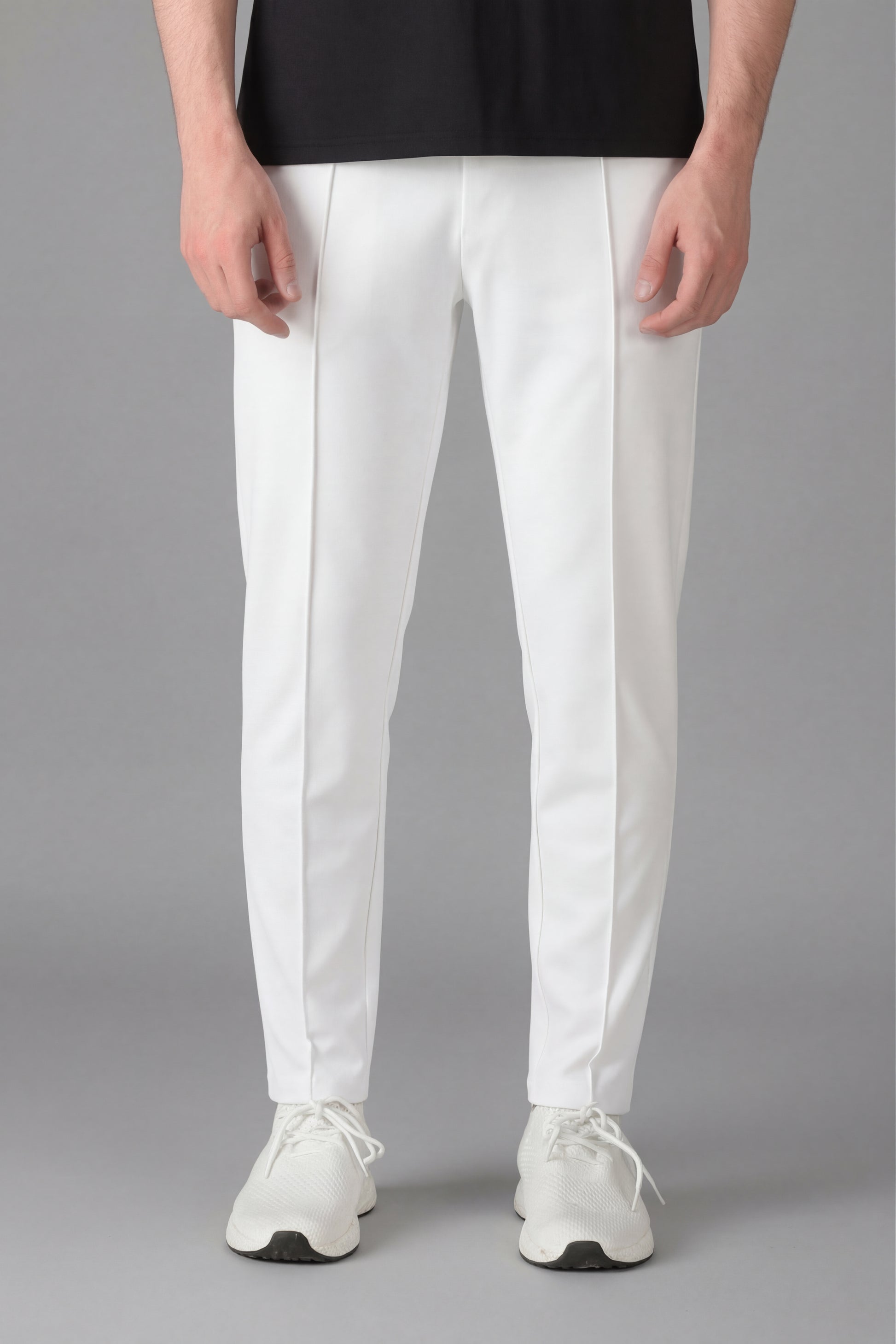 Person wearing white pants and white sneakers on a gray background