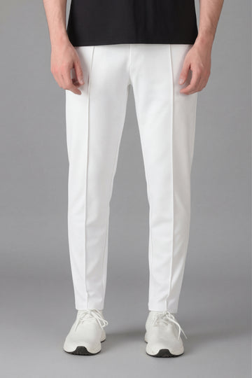 Person wearing white pants and white sneakers on a gray background