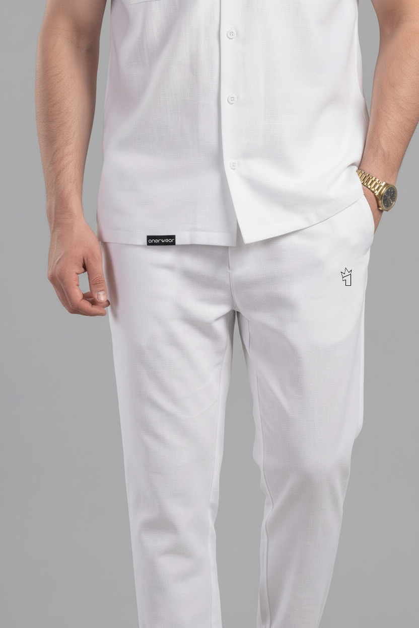 Person wearing a white shirt and pants with a brand label on a gray background